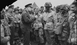 General Dwight D. Eisenhower gives the order of the Day. "Full victory-nothing else" to paratroopers in England, just before they board their airplanes to participate in the first assault in the invasion of the continent of Europe. 06/06/1944 RG 111 111-SC-194399 03061_2006_001 (Note: soldier's uniform insignia scratched out in original negative)